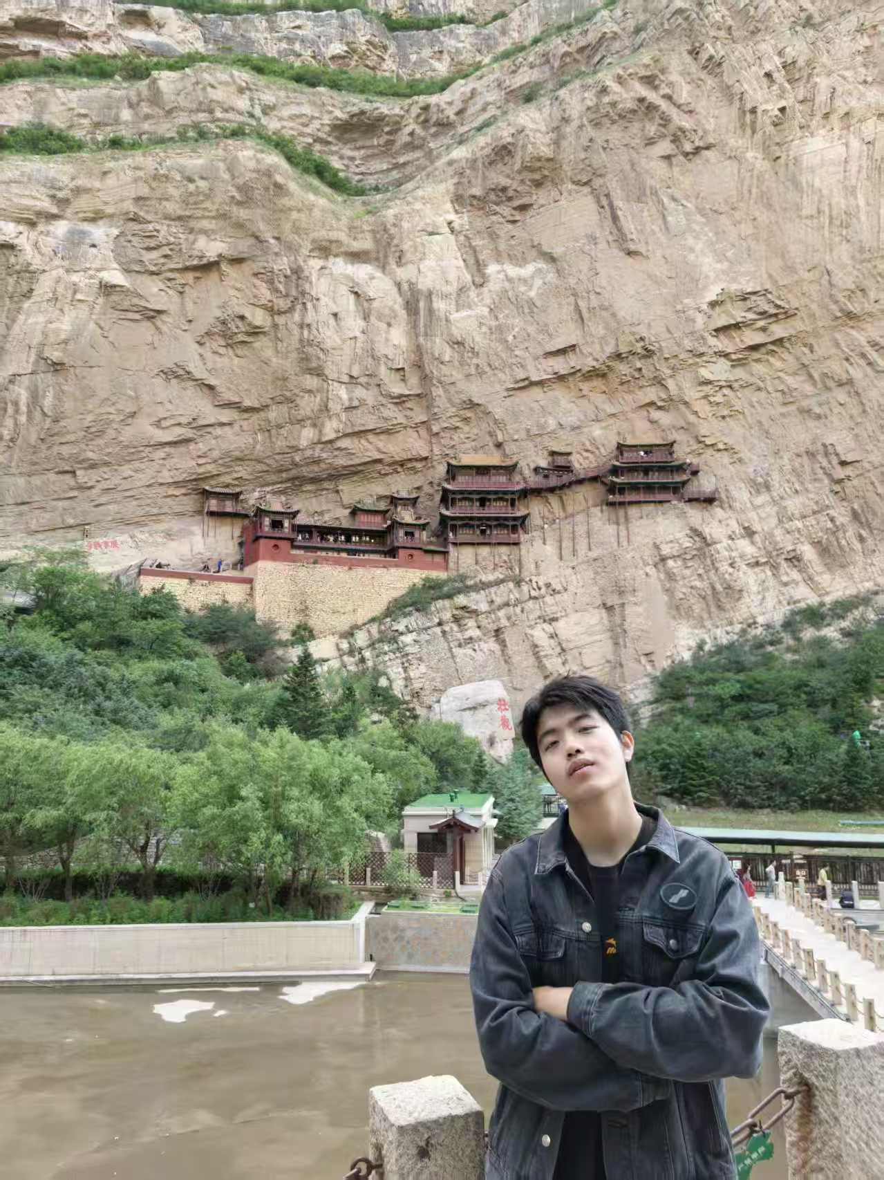 Haitong Lan standing in front of a cliffside temple